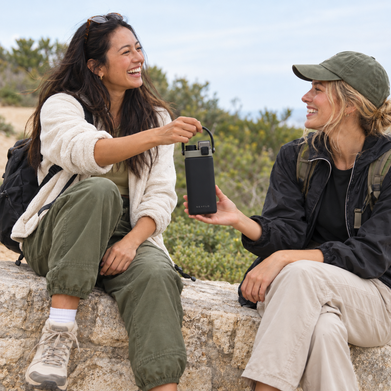 Two friends sharing a Shadow Black NEXFLO bottle during an outdoor break